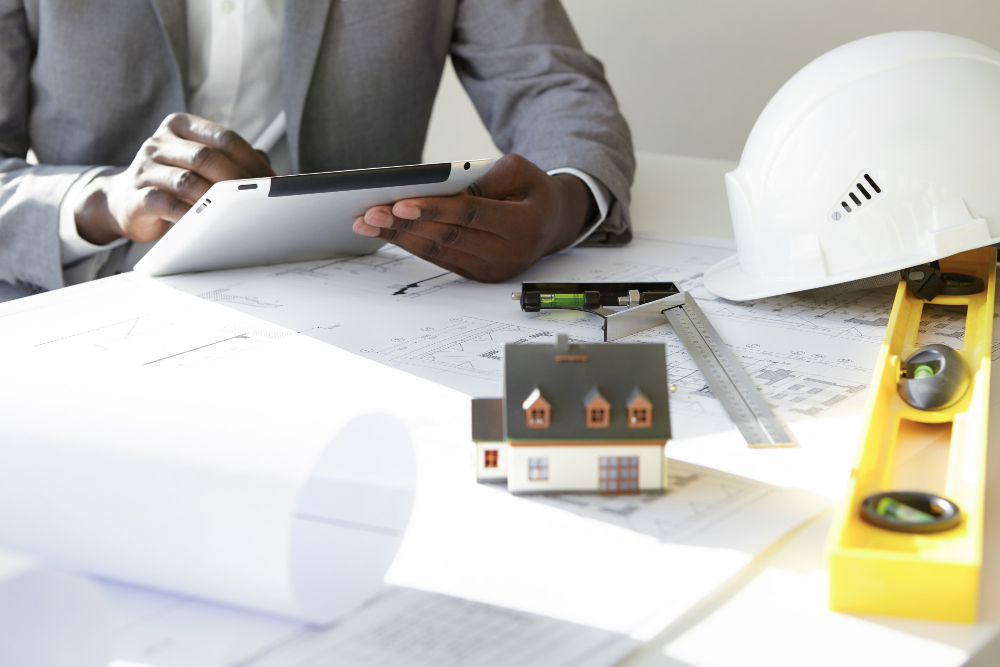 blueprint hard hat and person holding tablet at a table
