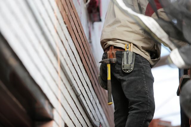 person on a ladder with a hammer on their belt