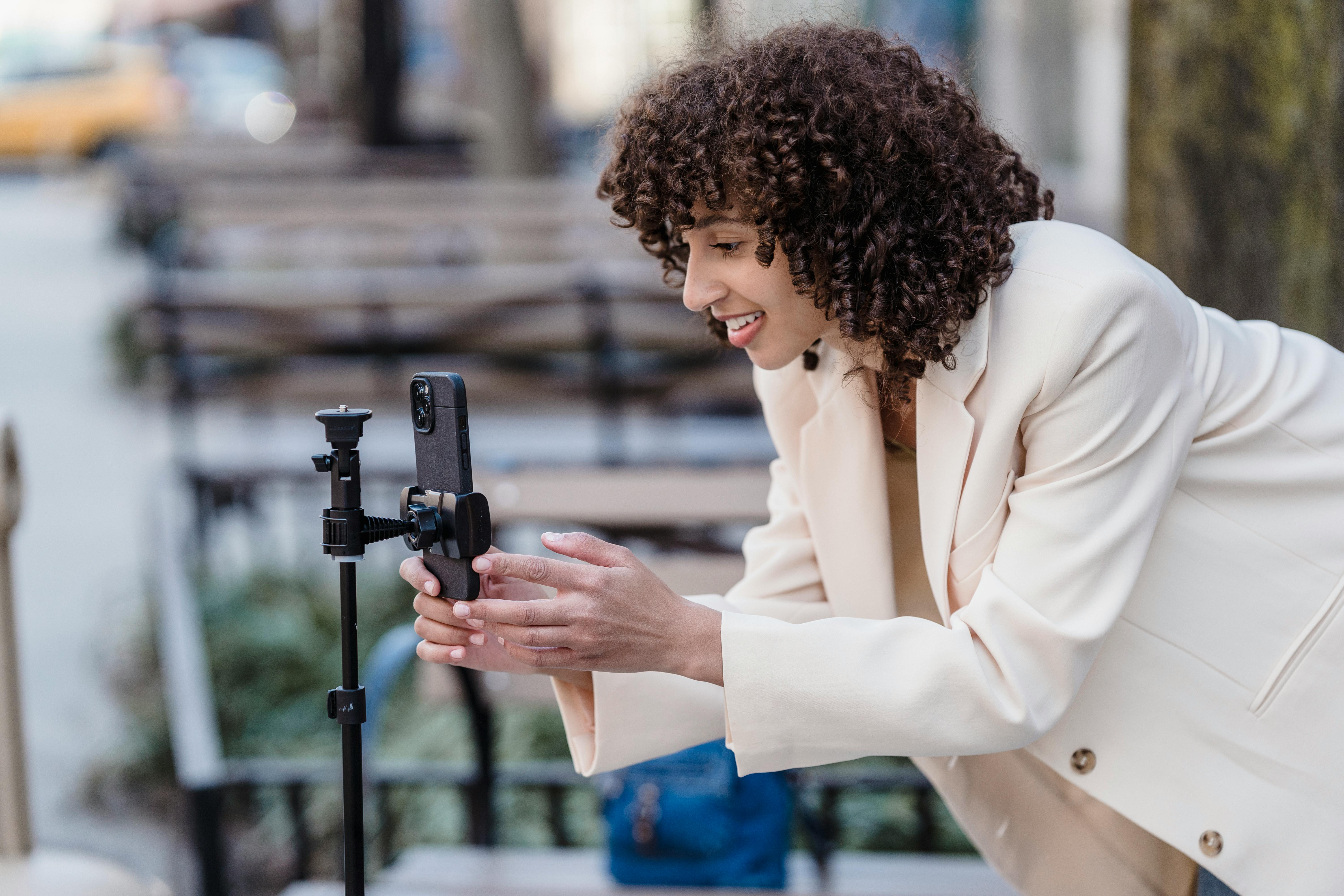 A person operating a smart phone using a tripod.
