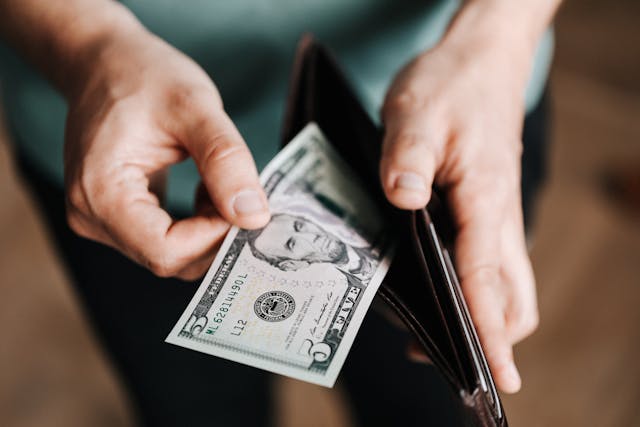 person taking money out of a leather wallet